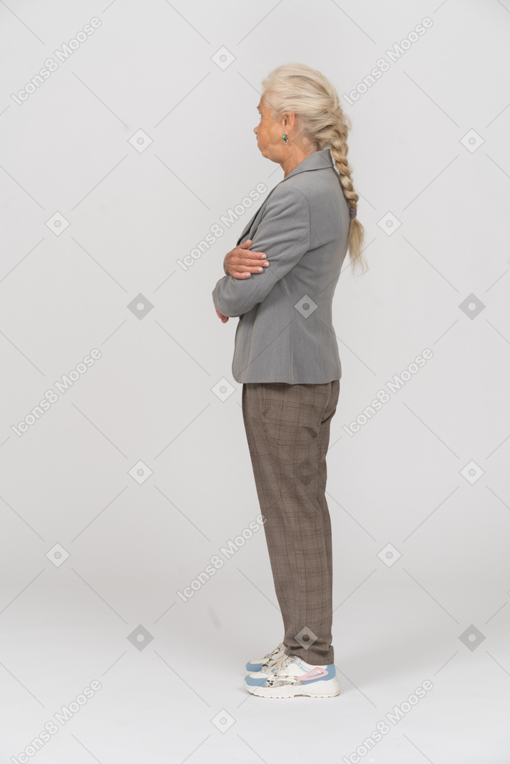 一位老妇人双臂交叉站在侧面的侧视图