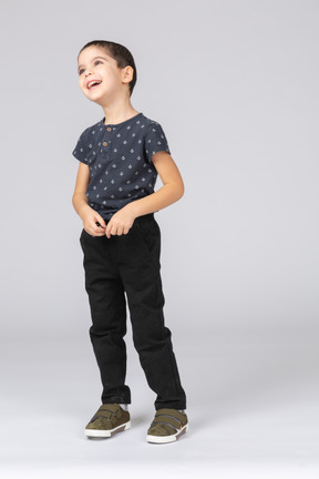 Vista frontal de un niño feliz en ropa casual mirando hacia arriba