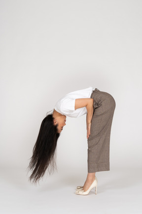 Side view of a young lady in breeches and t-shirt with messy hair bending down