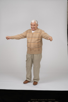 Front view of a happy old man in casual clothes standing with outstretched arms