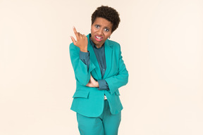 Black woman with a short haircut, wearing all blue, standing against a plain pastel background, looking emotional