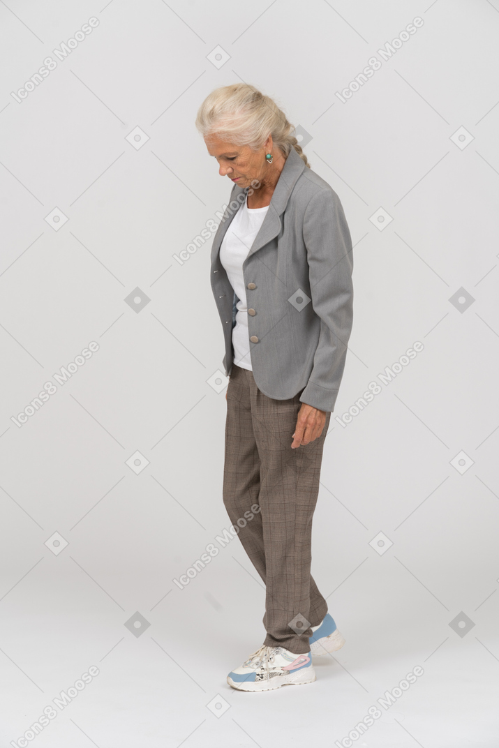 Seitenansicht einer alten dame im anzug, die mit den händen in den taschen steht