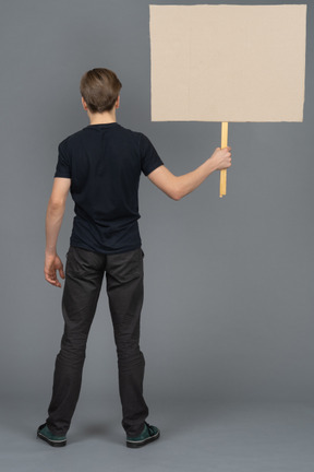 Joven serio de pie con un cartel en blanco