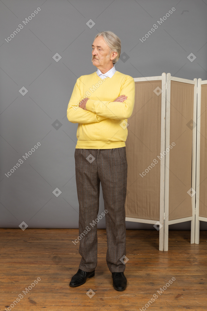 Front view of a curious old man crossing hands and looking aside