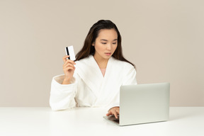 Bothered young asian woman doing online shopping