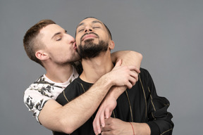 Close-up of a young caucasian man back hugging and kissing his partner