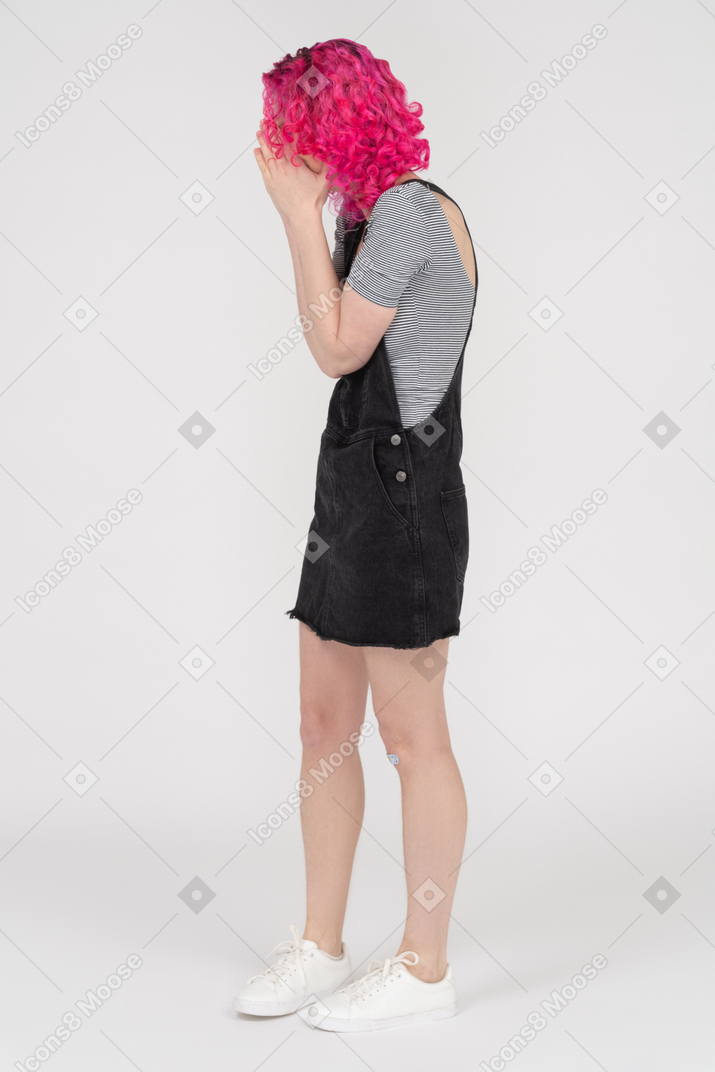 Menina com cabelo rosa cacheado e dor de cabeça