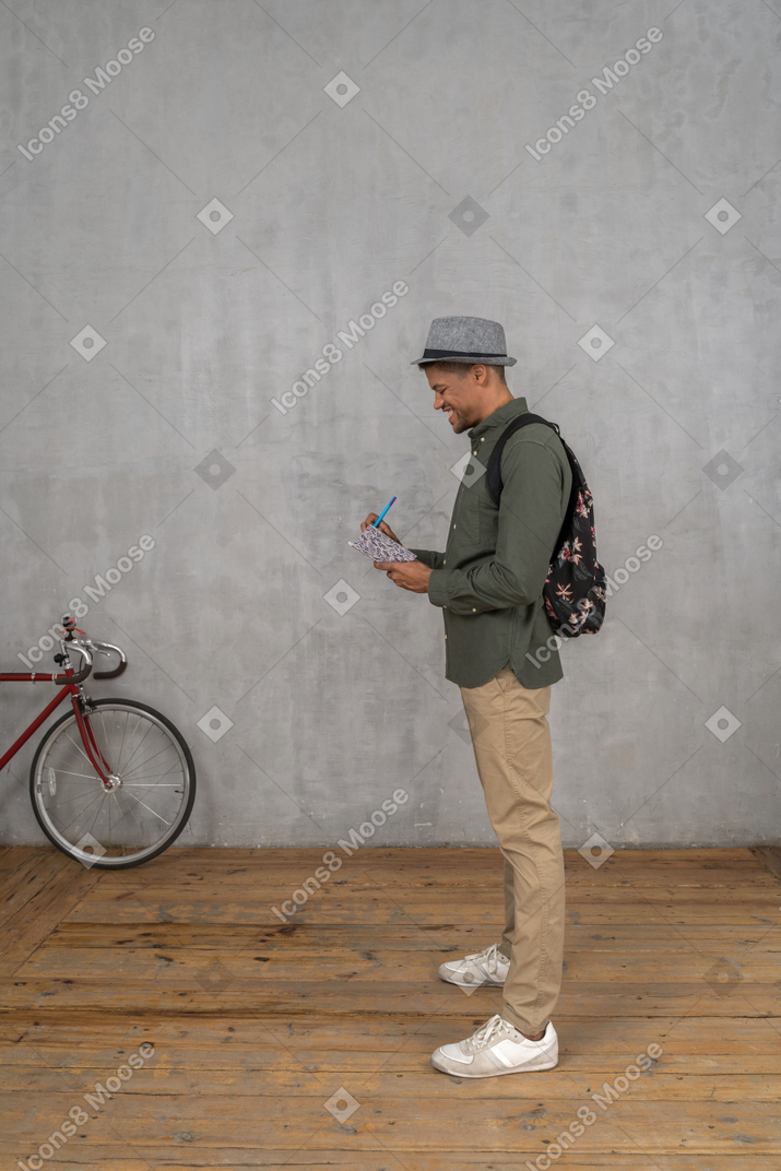 Homme prenant des notes dans un cahier et souriant