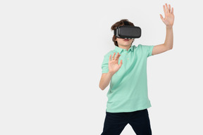 Boy in vr headset touching imaginary wall in digital world