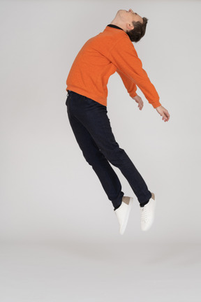 Junger mann im orange sweatshirt springen