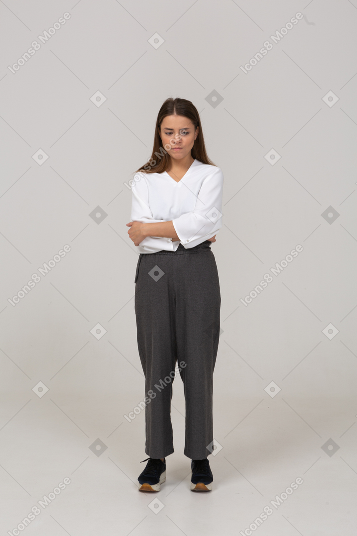 一位身着办公室服装的心烦意乱的年轻女士把手放在肚子上的前视图