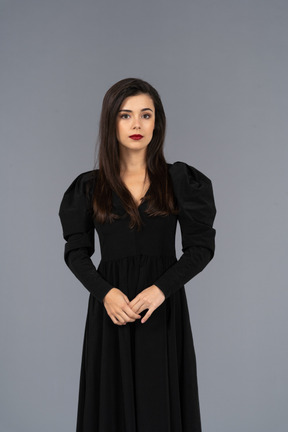 Front view of a young lady in a black dress standing still