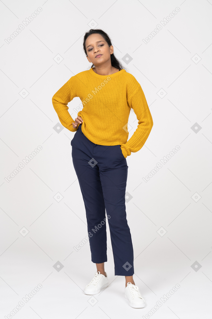Front view of a girl in casual clothes posing with hand on hip and hand in pocket and making faces