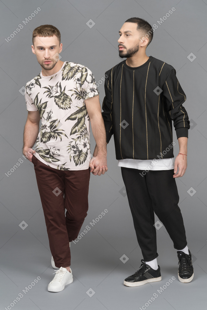 Zwei junge männer posieren, während sie sich an den händen halten