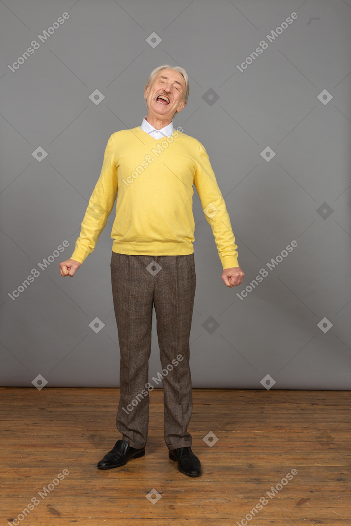Front view of a yawning man in a yellow pullover standing still and looking at camera