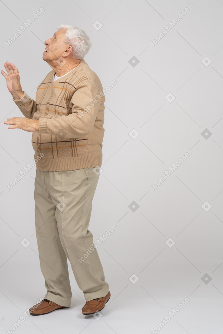 Вид сбоку на впечатленного старика в повседневной одежде, смотрящего вверх