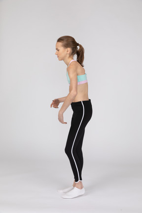 Vista lateral de uma adolescente fraca em roupas esportivas inclinada para a frente
