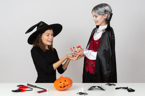 Boy in vampire costume showing candies to his mom in cat costume