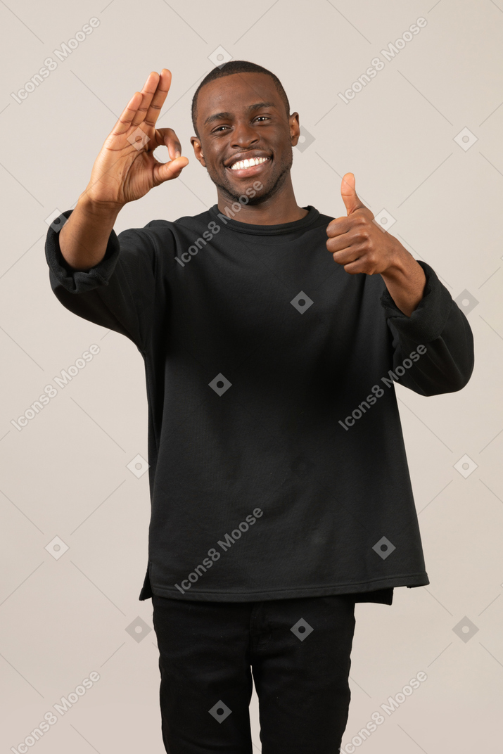 Smiling young man showing thumb up and ok sign