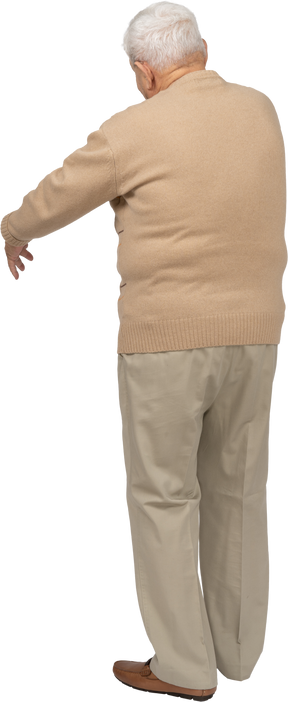 Vista trasera de un anciano con ropa informal de pie con el brazo extendido