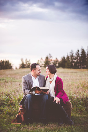 Couple assis avec un livre à l'extérieur