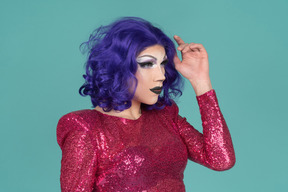 Retrato de una drag queen con un vestido rosa de lentejuelas arreglándose el pelo