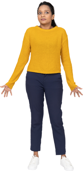 Front view of a confused girl in casual clothes standing with outstretched arms and looking up