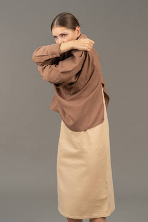 Mujer joven tirando de su camisa sobre la cabeza con los brazos cruzados