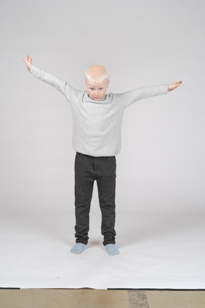 Vista frontal de um menino abrindo os braços como se estivesse voando