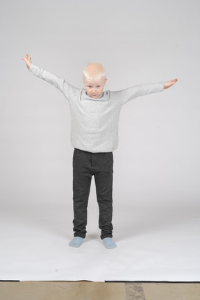 Front view of a little boy spreading his arms as if flying