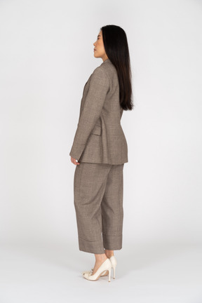 Three-quarter back view of a young lady in brown business suit closing her eyes