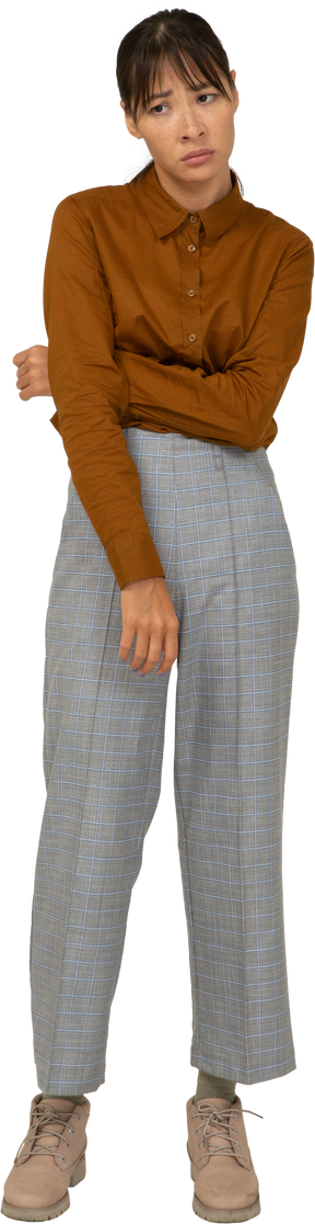 Vista frontal de una joven mujer asiática retirada en calzones y blusa tocando el estómago