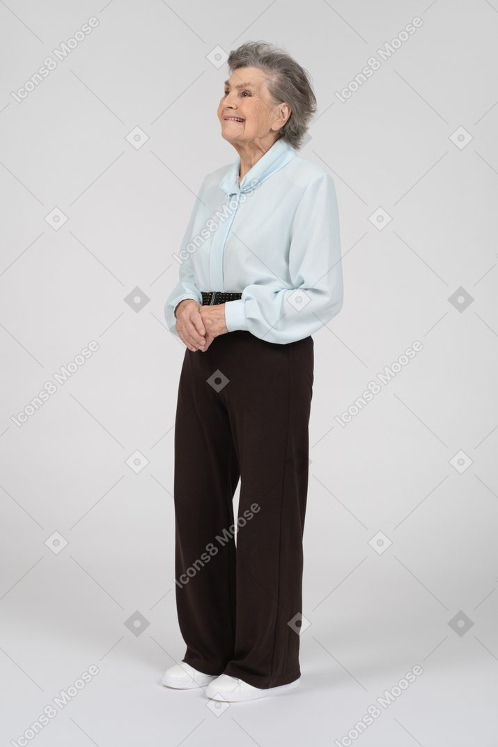 Вид сбоку на пожилую женщину, гримасничающую со сложенными руками