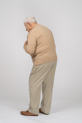 Side view of an old man in casual clothes explaining something