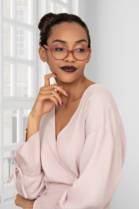 A thoughtful woman wearing glasses and a pink top