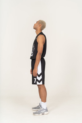 Vista laterale di un giovane giocatore di basket maschile che guarda in alto