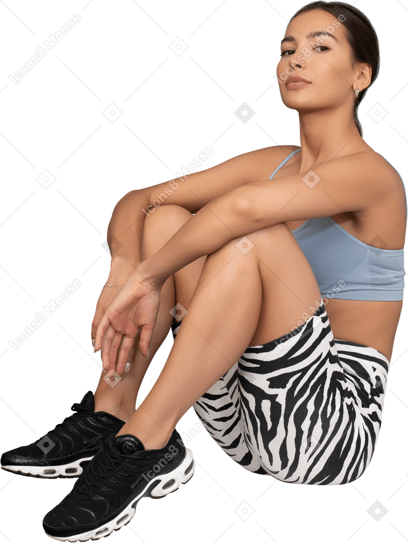Retrato de una atleta femenina sentada con confianza en un cubo