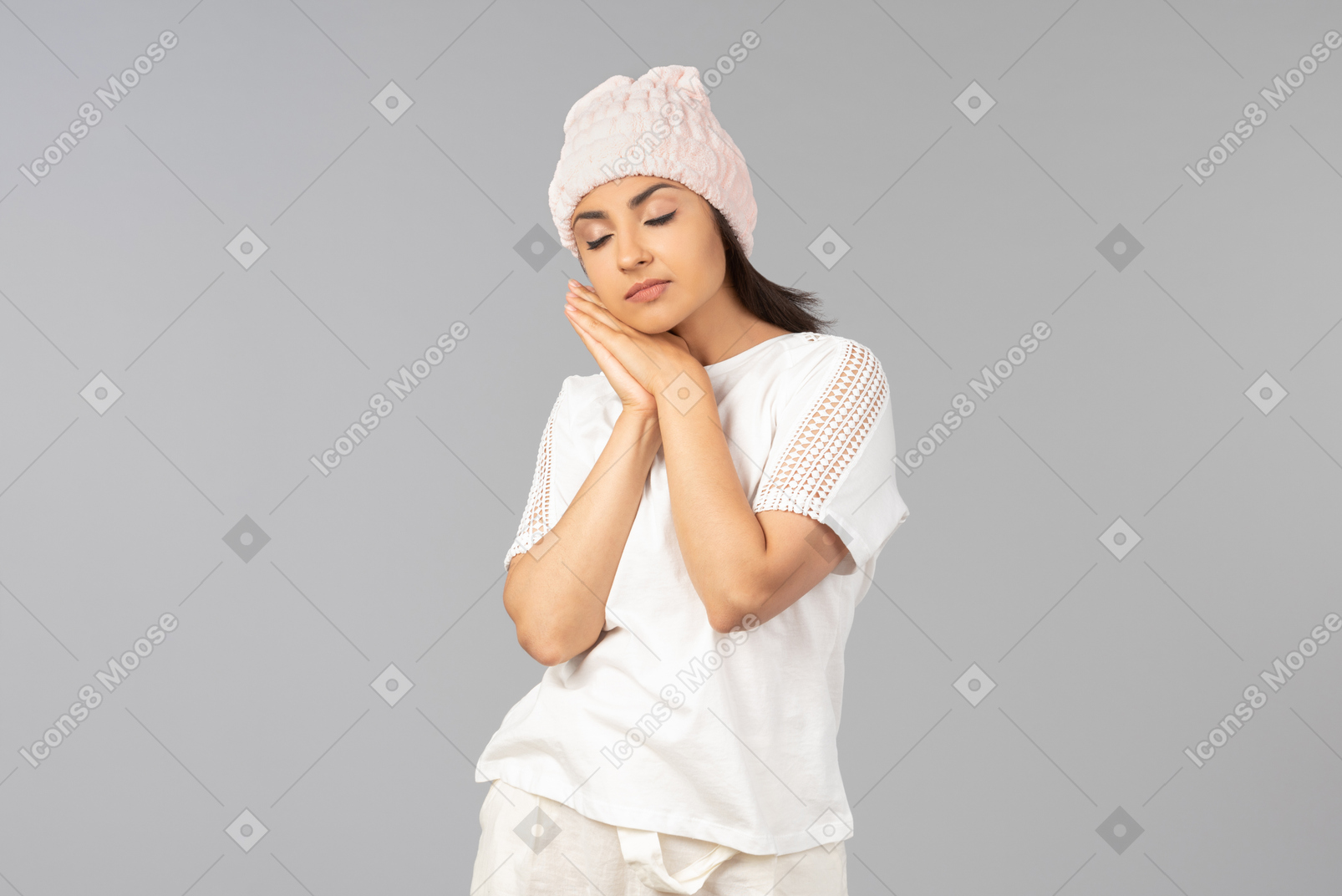 Joven india en ropa cómoda y sombrero rosa durmiendo en la mano