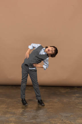 Front view of a boy in grey suit standing with hands on hips