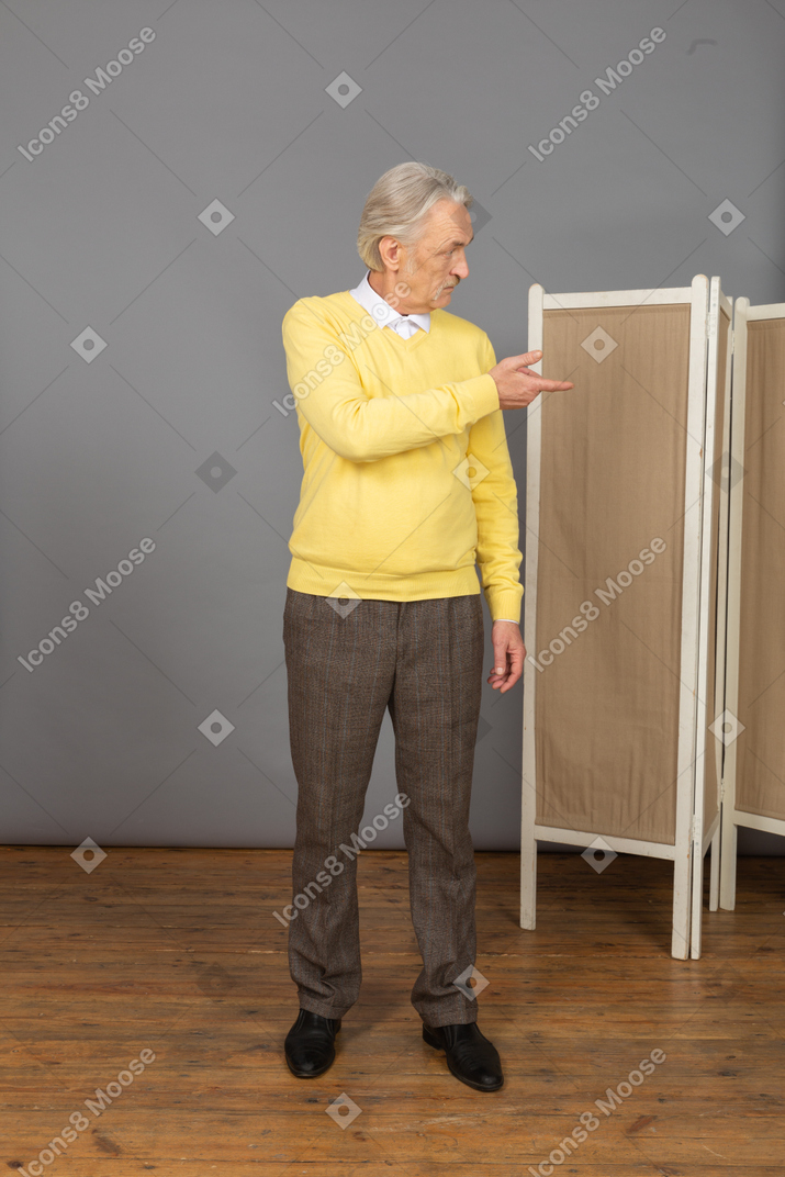 Front view of a questioning old man raising hand while looking aside
