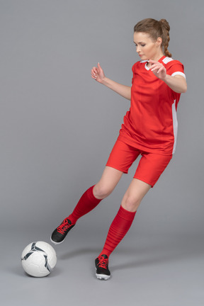 A sporty female player is about to kick the ball