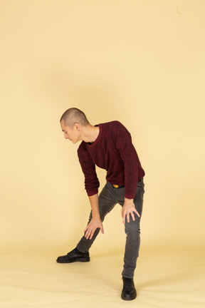 Front view of a young man in red pullover making a lunge