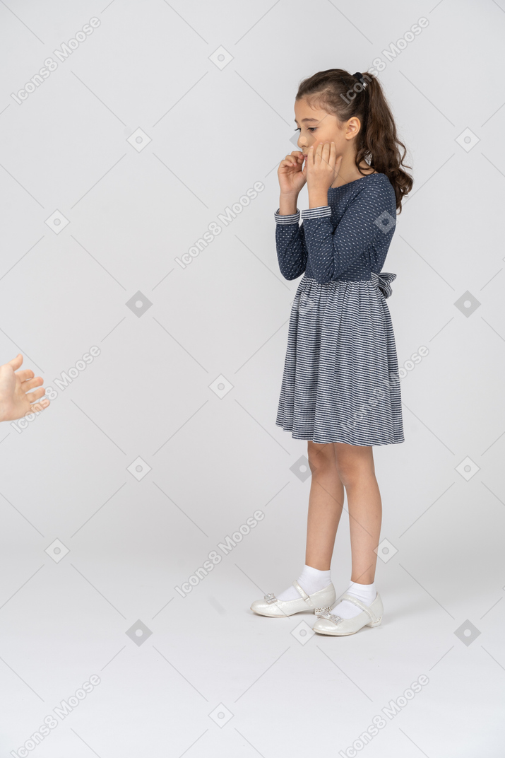 Visão de três quartos de uma garota tocando e apertando suas bochechas
