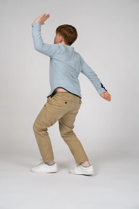 Back view of a young boy raising his hand