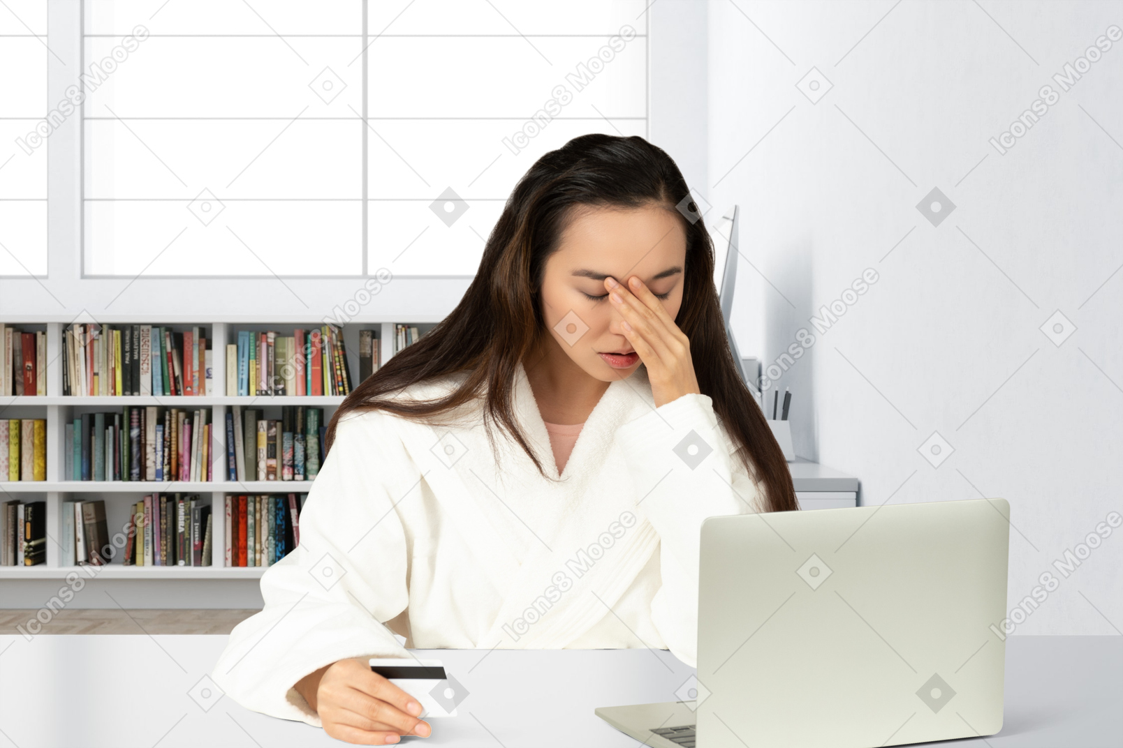 A young woman with facepalm sitting at a desk with laptop holding a credit card
