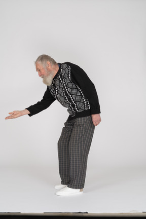 Side view of old man bending down and giving hand