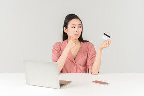 Triste olhando jovem mulher asiática fazendo compras on-line