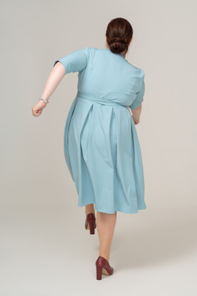 一个穿蓝色裙子的女人走路的后视图