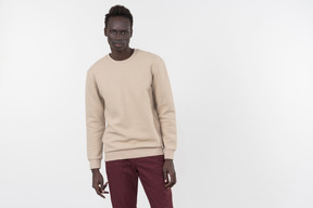 A young black man in a grey sweater standing alone on the white background