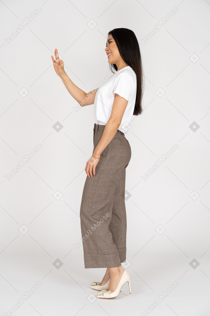 Side view of a smiling young woman in breeches showing ok sign